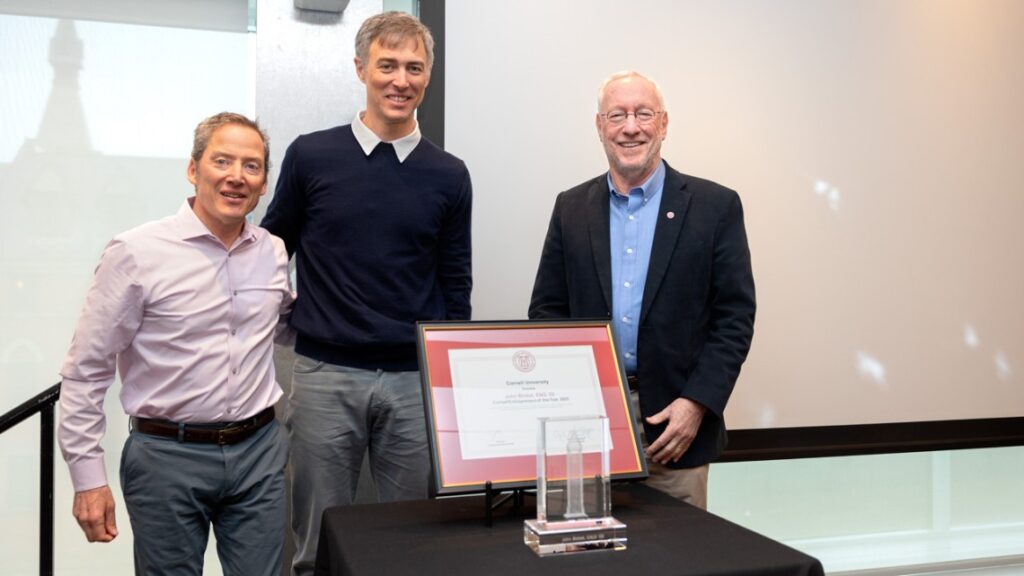 Three men standing in front of a framed certificate