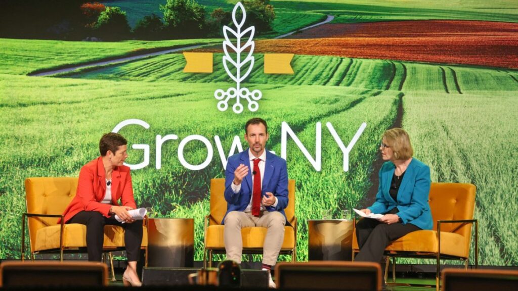 three people sitting on stage at GrowNY event