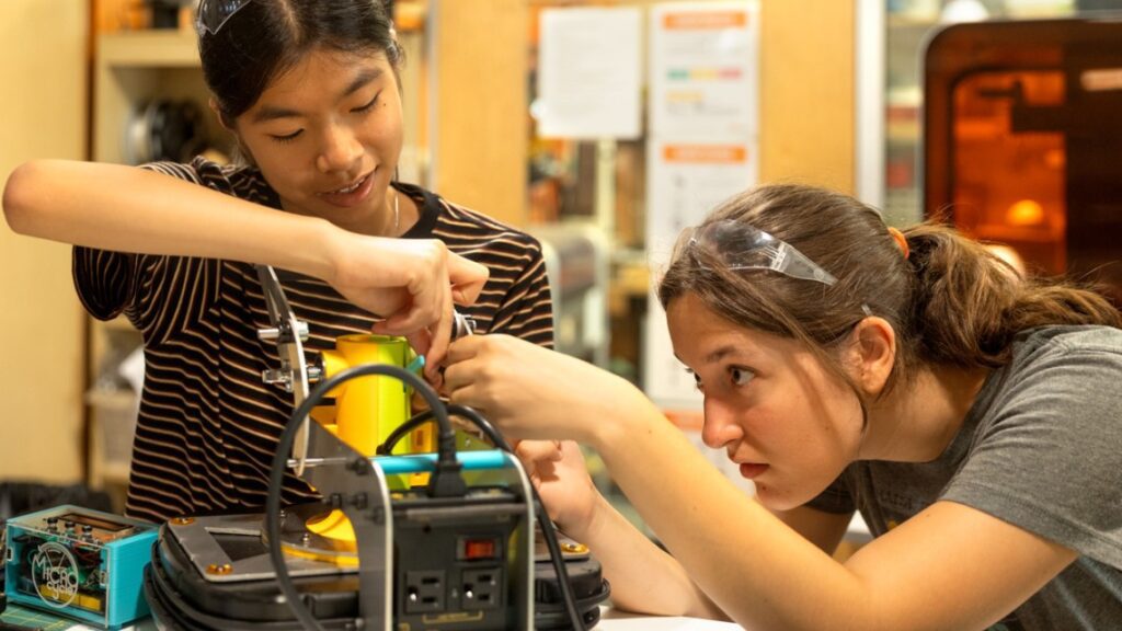 two girls working on an electric project in a lab