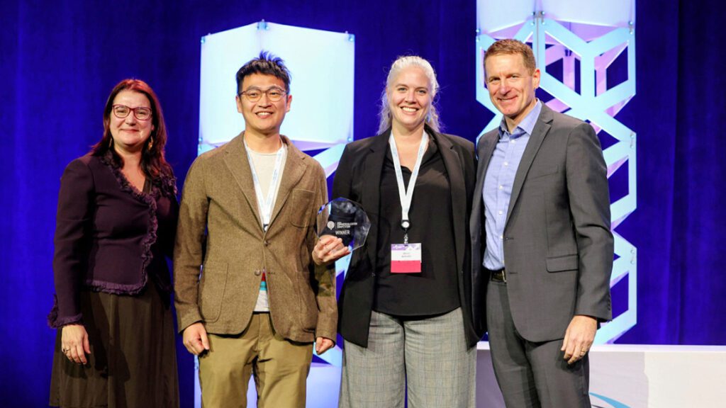 Group of four people standing together holding crystal award