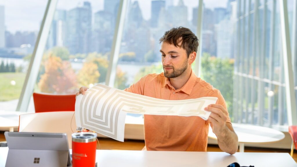 Photo of a man holding up sheet of paper with a design on it.