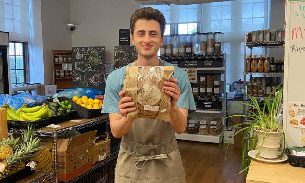 man standing in food market holding a paper bagged item