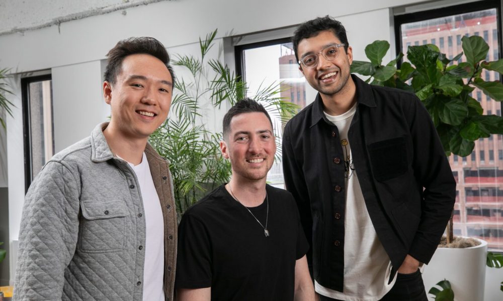 three men standing in front of plants