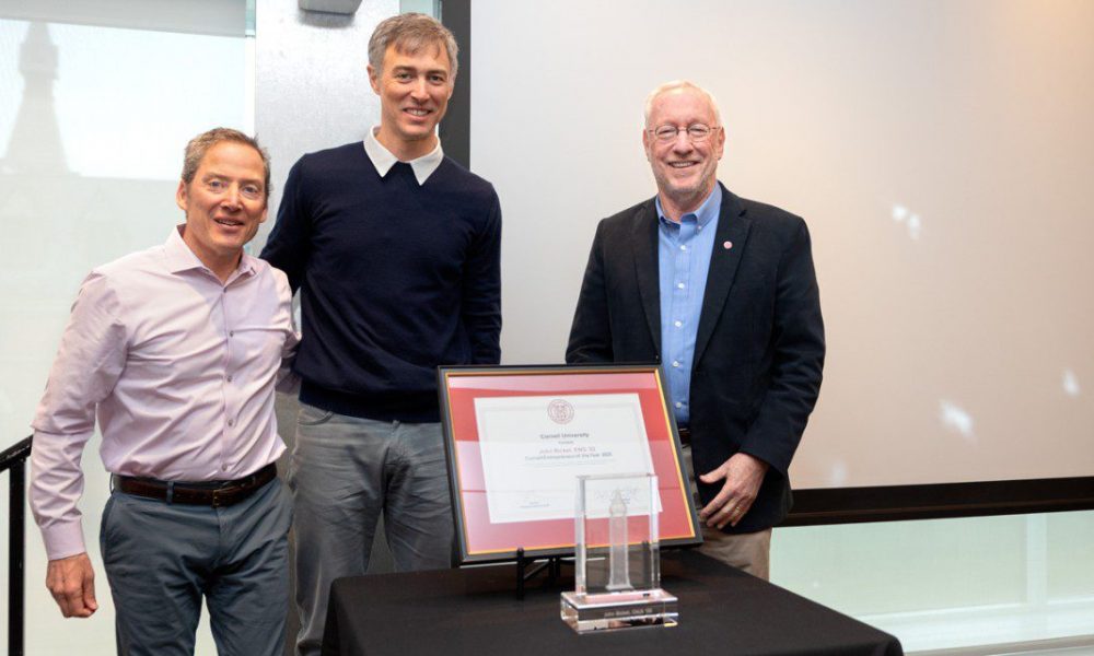 Three men standing in front of a framed certificate