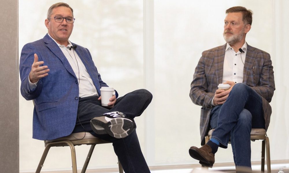 Two men sitting in chairs with legs crossed