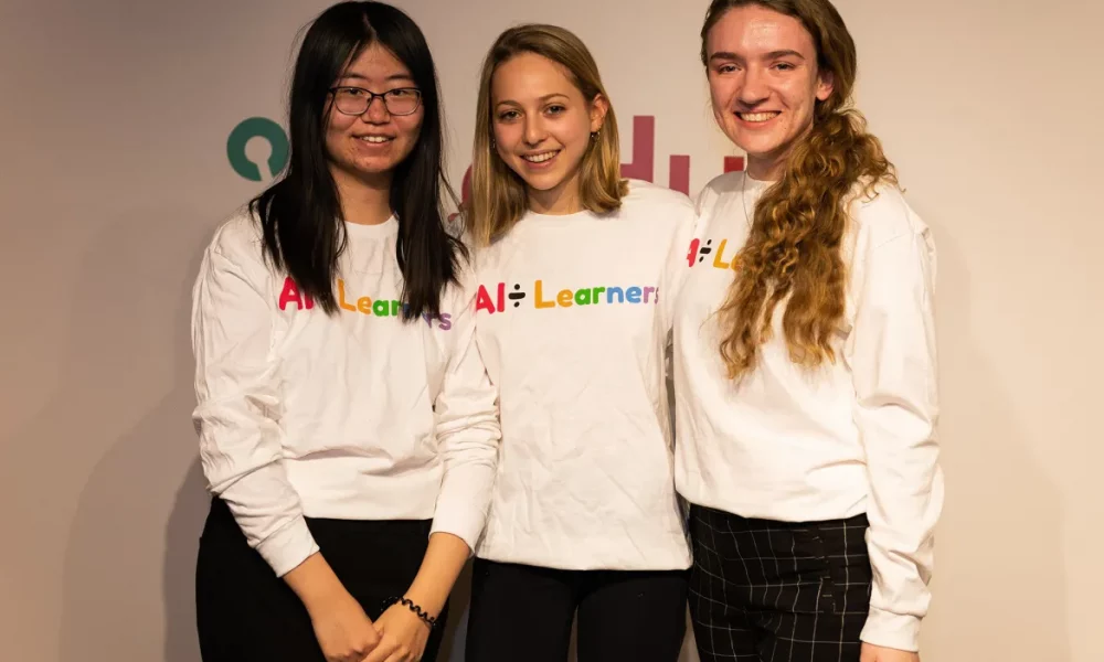 three students standing in front of their logo