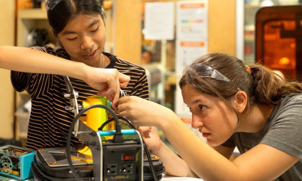 two girls working on an electric project in a lab