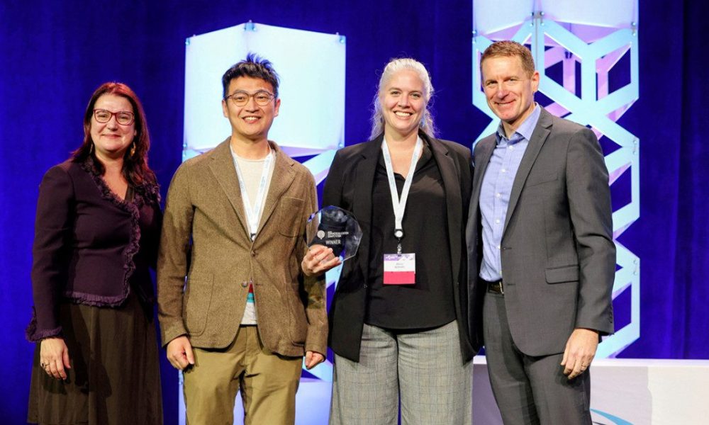 Group of four people standing together holding crystal award