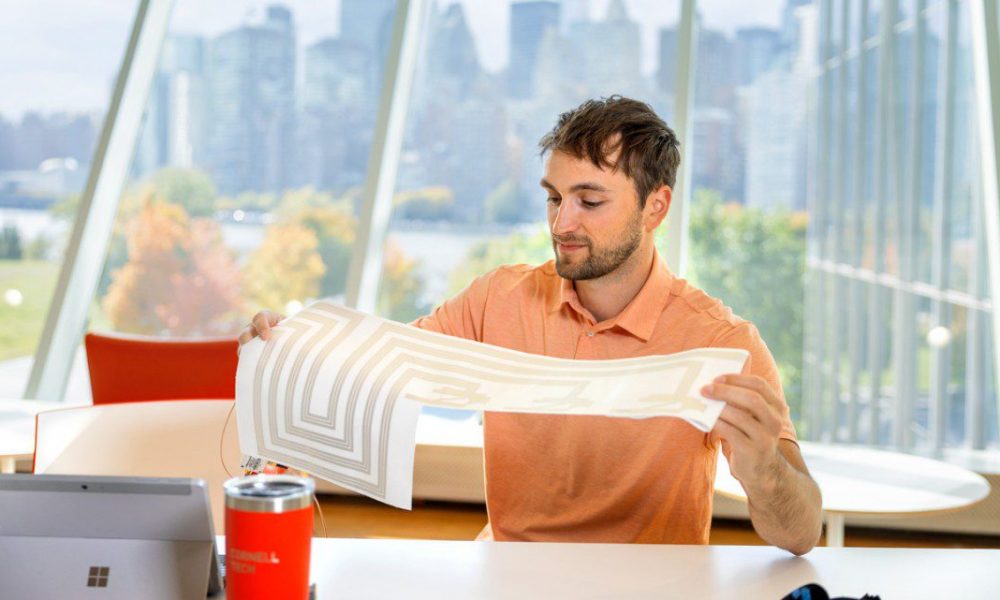 Photo of a man holding up sheet of paper with a design on it.