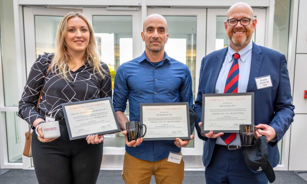 Three people standing next to each other holding certificates and coffee mugs.