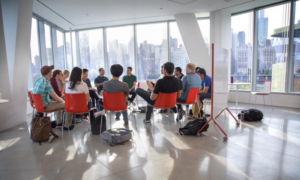 Group of people sitting in red chairs in a Cornell Tech campus building