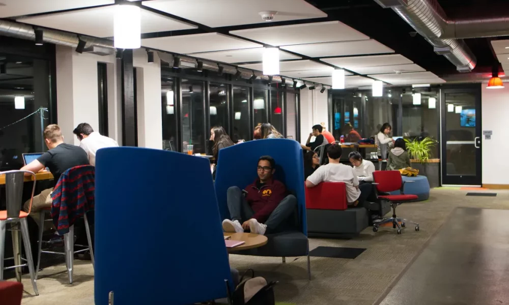 students gathered in lobby space in interesting blue chairs lounging, enjoying each other's company