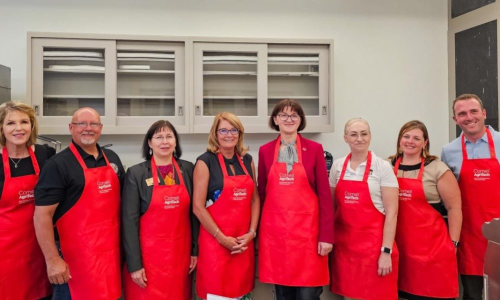Food Innovation Lab cohort standing in lab wearing red aprons to celebrate