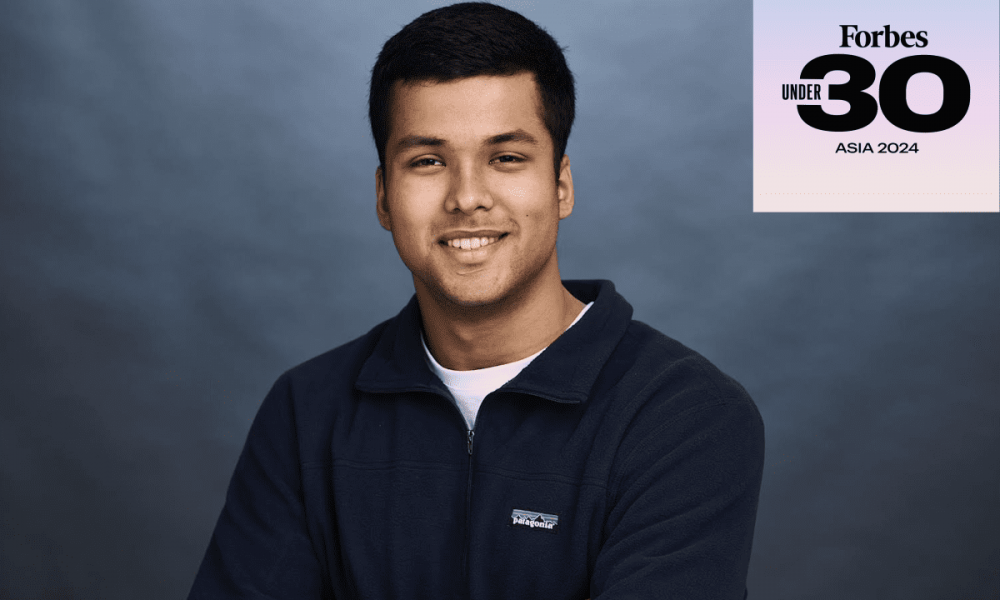 professional photo of Kush Jain wearing navy pullover and arms crossed in front. Forbes 30 under 30 logo in top right corner.