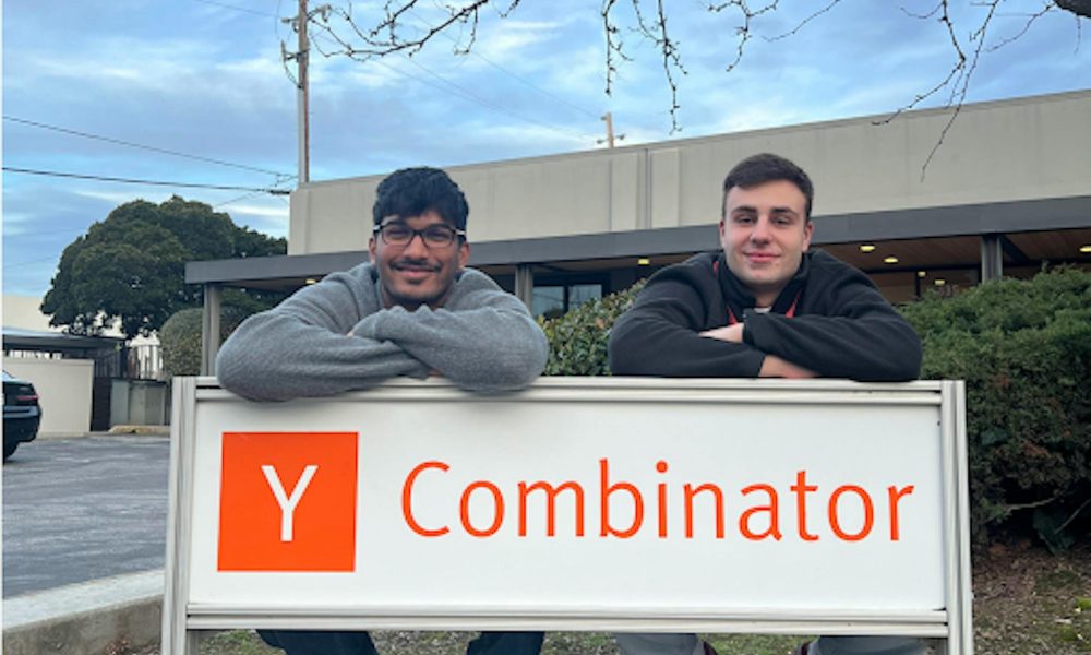two men leaning over a sign that says Y Combinator