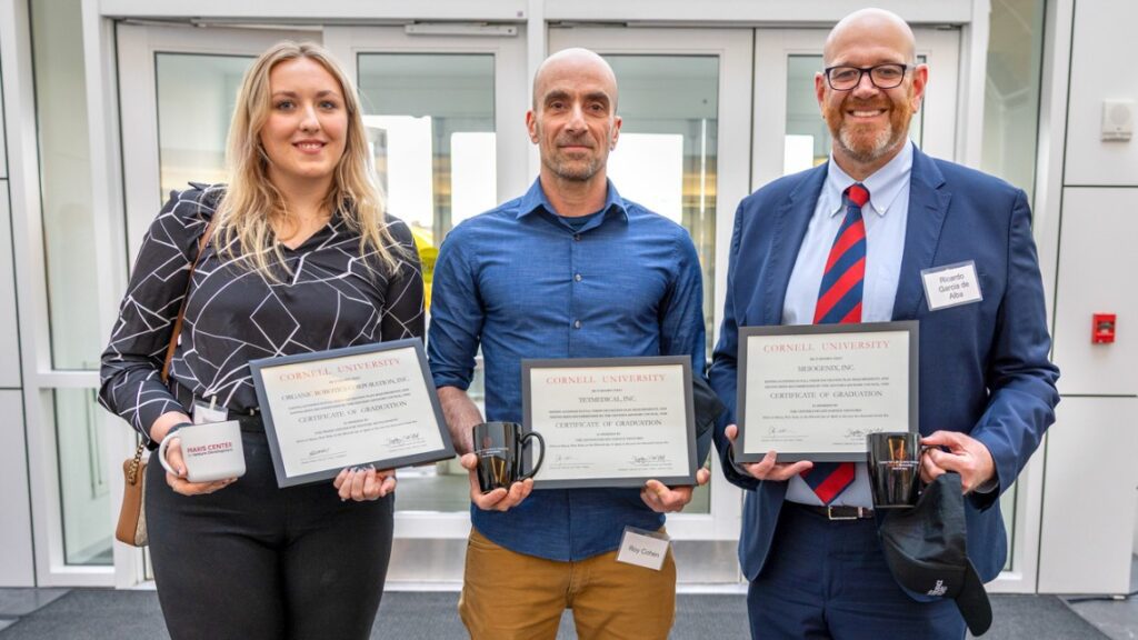 Three people standing next to each other holding certificates and coffee mugs.