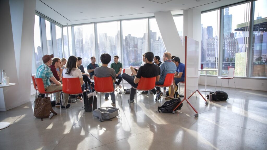 Group of people sitting in red chairs in a Cornell Tech campus building