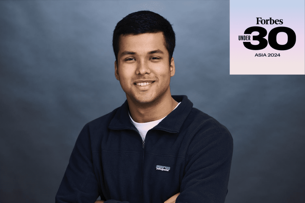 professional photo of Kush Jain wearing navy pullover and arms crossed in front. Forbes 30 under 30 logo in top right corner.