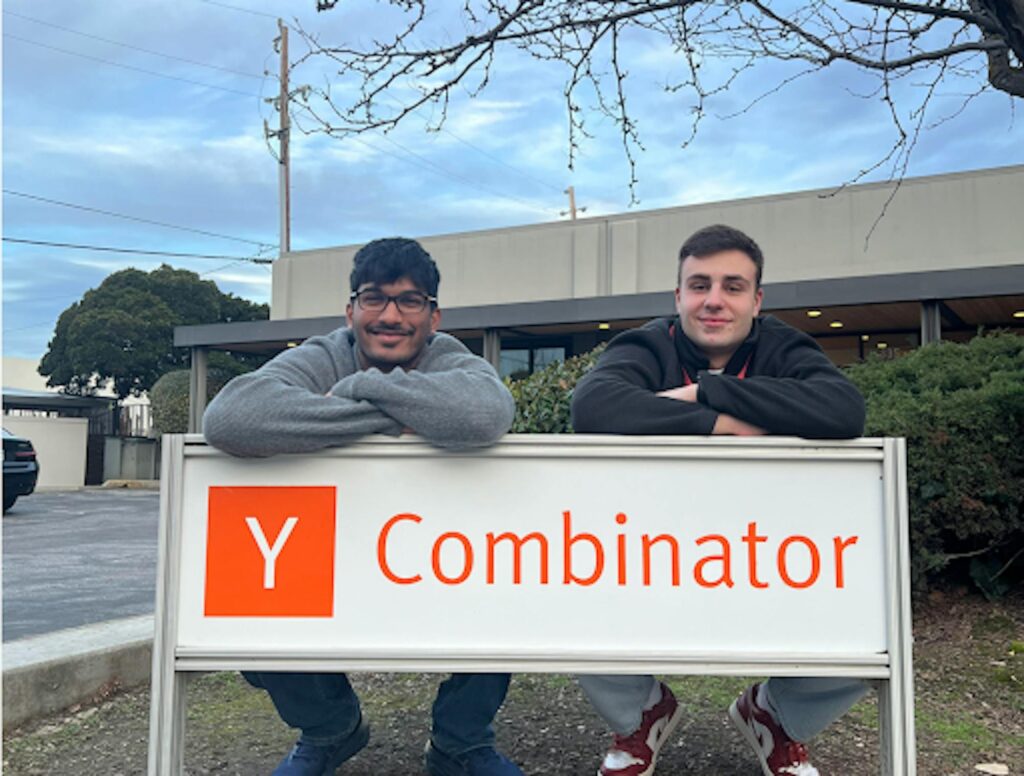 two men leaning over a sign that says Y Combinator